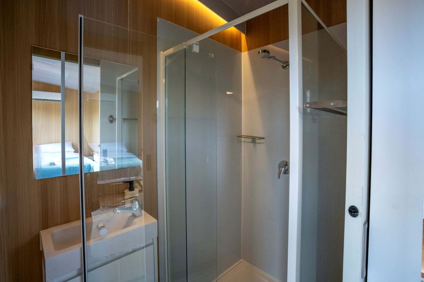 Un baño moderno con cabina de ducha de vidrio, un espejo y un lavamanos con toallero.