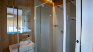 Un baño moderno con cabina de ducha de vidrio, un espejo y un lavamanos con toallero.