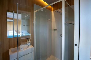 A modern bathroom with a glass shower enclosure, a mirror, and a sink with a towel rack.