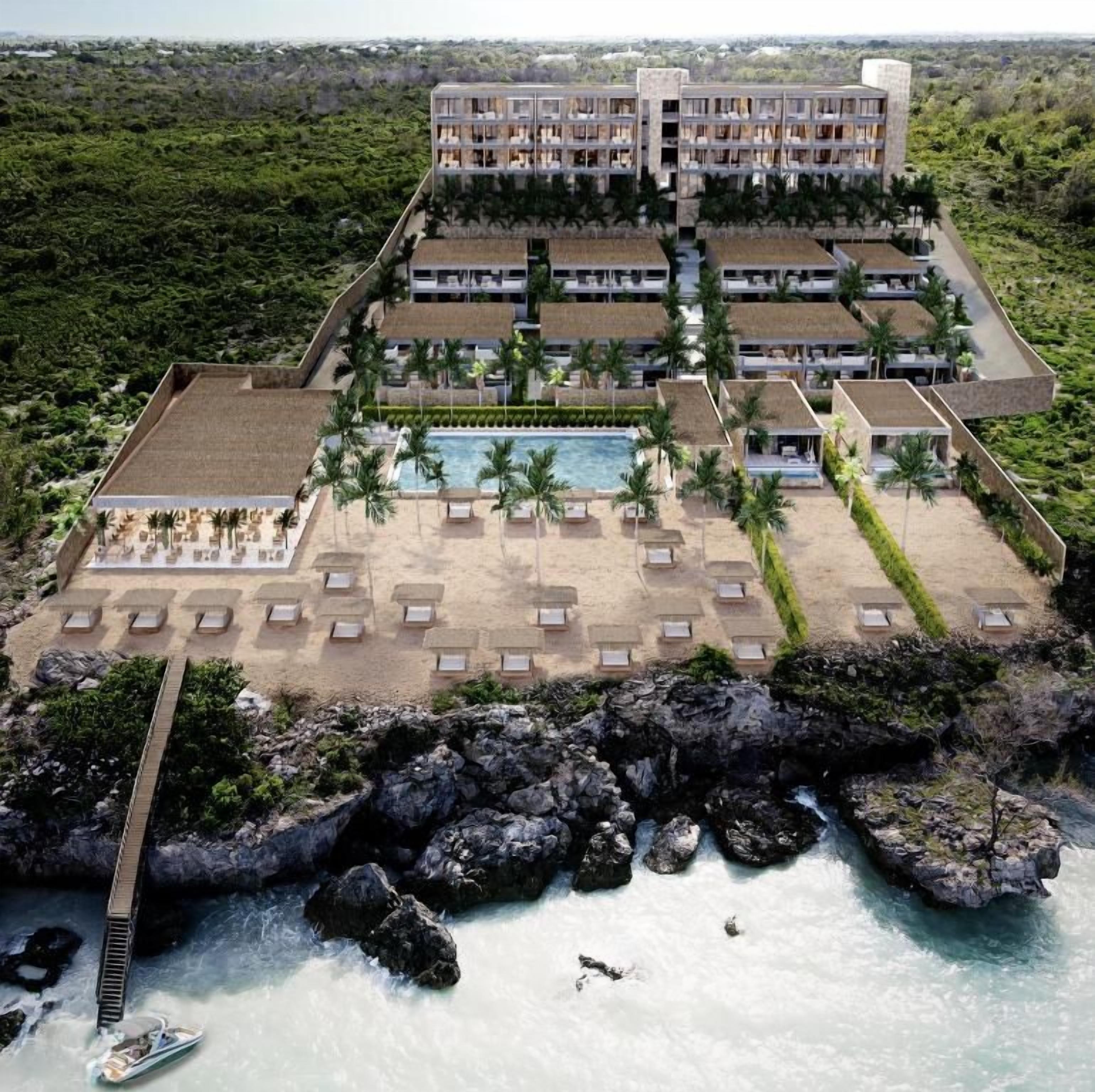 A resort with multiple buildings, a swimming pool, and a rocky coastline.