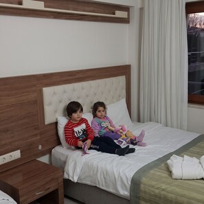 A bed with a wooden headboard, a bedside table, and a window with curtains.