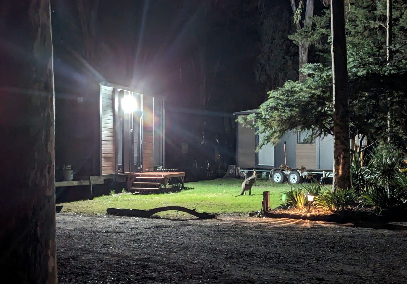 A campsite with a wooden structure, a table, and a trailer.