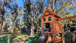 A playground with a wooden playhouse, a slide, and a climbing structure. - Romantic Glamping Getaway near the Grampians: Cozy Tiny House Rental in Dadswells Bridge, Victoria (Dadswells Bridge)