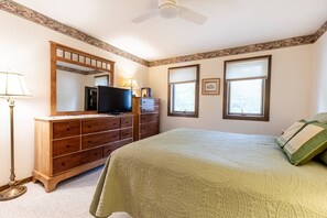 A bedroom with a bed, dresser, television, and two windows. - New Waterfront Thomas Point Retreat with Private Beach, Dock, Billiards & Parking (Annapolis)