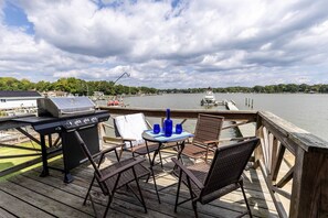 A deck with a grill, chairs, and a table with blue glassware. - New Waterfront Thomas Point Retreat with Private Beach, Dock, Billiards & Parking (Annapolis)