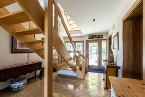 A wooden staircase leading to a second floor, a dining area with a table and chairs, and a Buddha statue on a pedestal. - New Waterfront Thomas Point Retreat with Private Beach, Dock, Billiards & Parking (Annapolis)