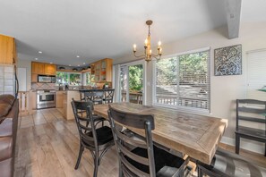 A modern kitchen with a dining area, wooden cabinets, and a chandelier. - Hall Court Overlook - Hot Tub (Stateline)