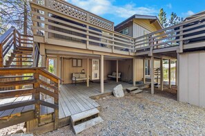A two-story wooden cabin with a deck, outdoor seating, and a covered porch area. - Hall Court Overlook - Hot Tub (Stateline)