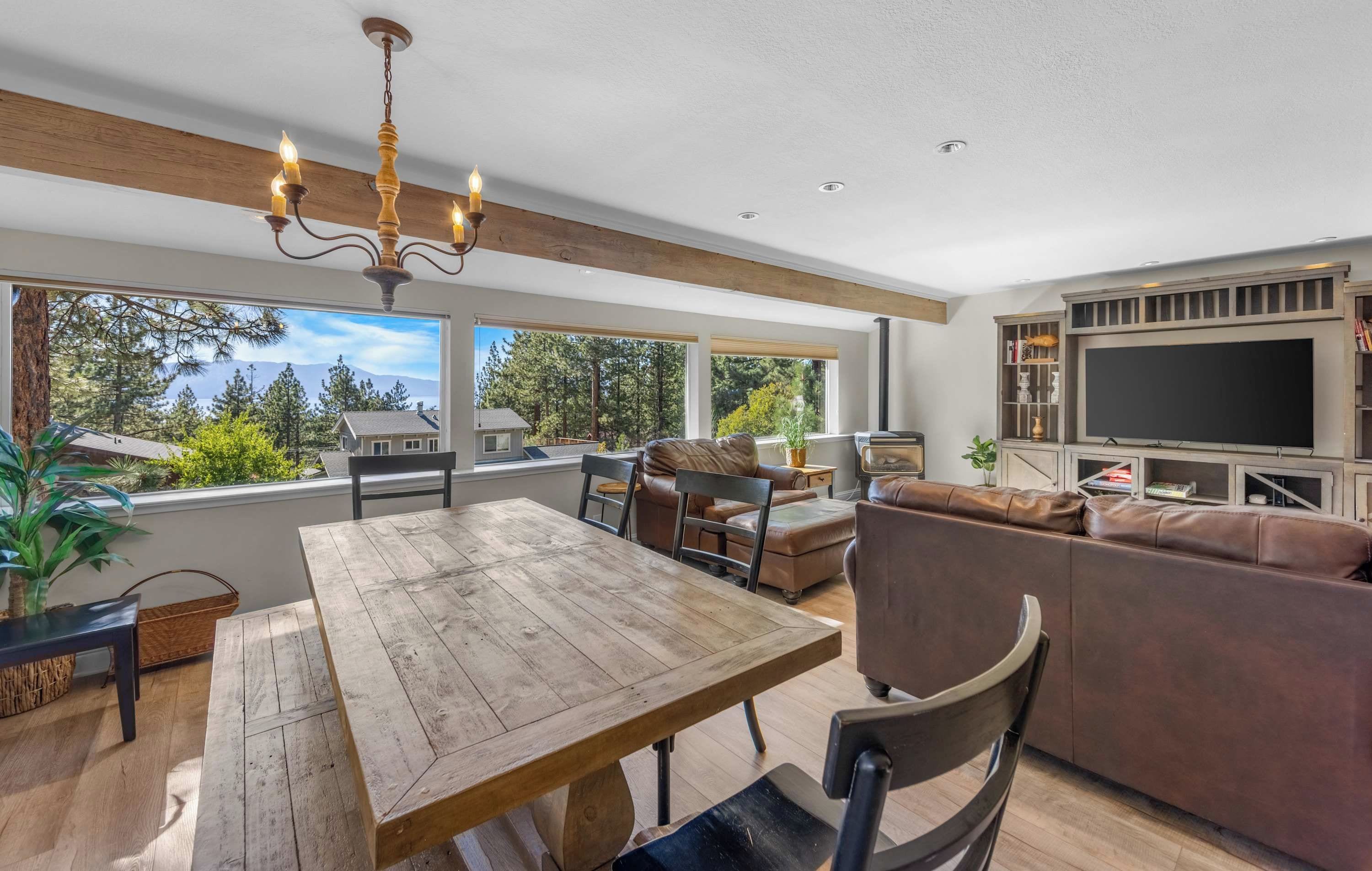 A spacious living area with a wooden dining table, leather sofa, and a large TV.