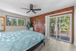 A bedroom with a bed, a ceiling fan, a large window, and a sliding glass door leading to an outdoor area. - Hall Court Overlook - Hot Tub (Stateline)