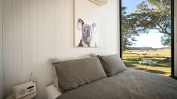 Quarto com cama, rádio e um quadro de um coala na parede.