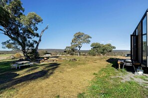 Una propiedad con un amplio patio, mesas de picnic y una parrilla.