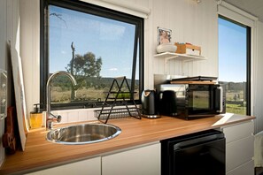 A kitchen with a stainless steel sink, a black coffee maker, a microwave, and a wooden countertop.
