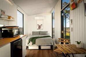 Ein kleines Schlafzimmer mit Bett, einer Bank und Blick ins Freie.