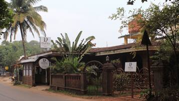 A hotel entrance with a sign reading 'Panya Courtyard Hotel' and a gated entrance with a wrought iron gate.
