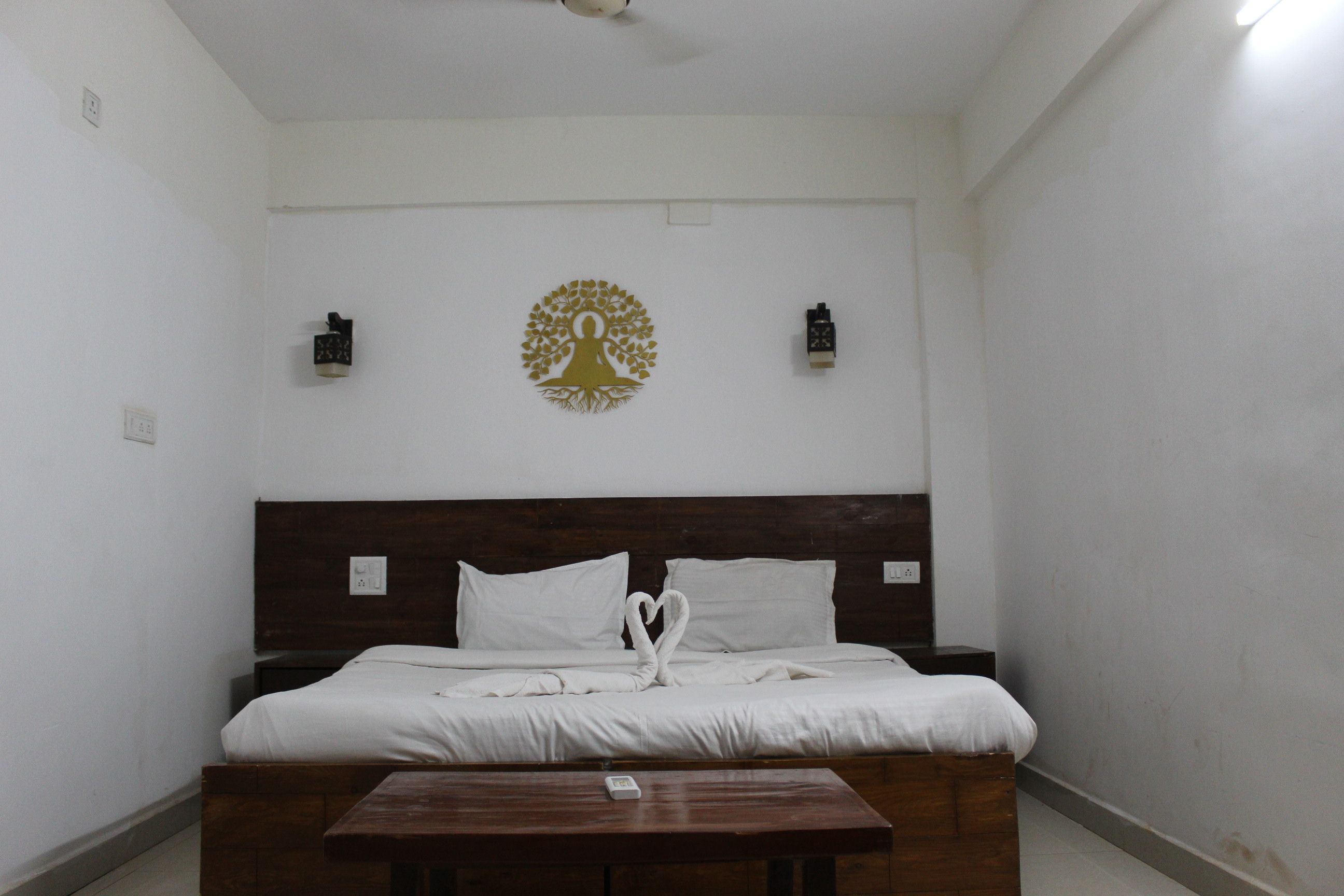 Ein Schlafzimmer mit hölzernem Kopfteil, einem Bett mit weißer Bettwäsche, einem kleinen Holztisch und einem dekorativen Wandbild über dem Bett.