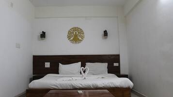 Ein Schlafzimmer mit hölzernem Kopfteil, einem Bett mit weißer Bettwäsche, einem kleinen Holztisch und einem dekorativen Wandbild über dem Bett.