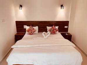 Ett hotellrum med en stor säng, två sängbord och två väggmonterade lampor.