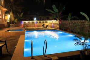 En swimmingpool med kakel runt kanten och en liten yta för solstolar.