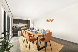 Una zona de menjador moderna amb una taula de fusta preparada per a sis persones, envoltada de cadires taronja.