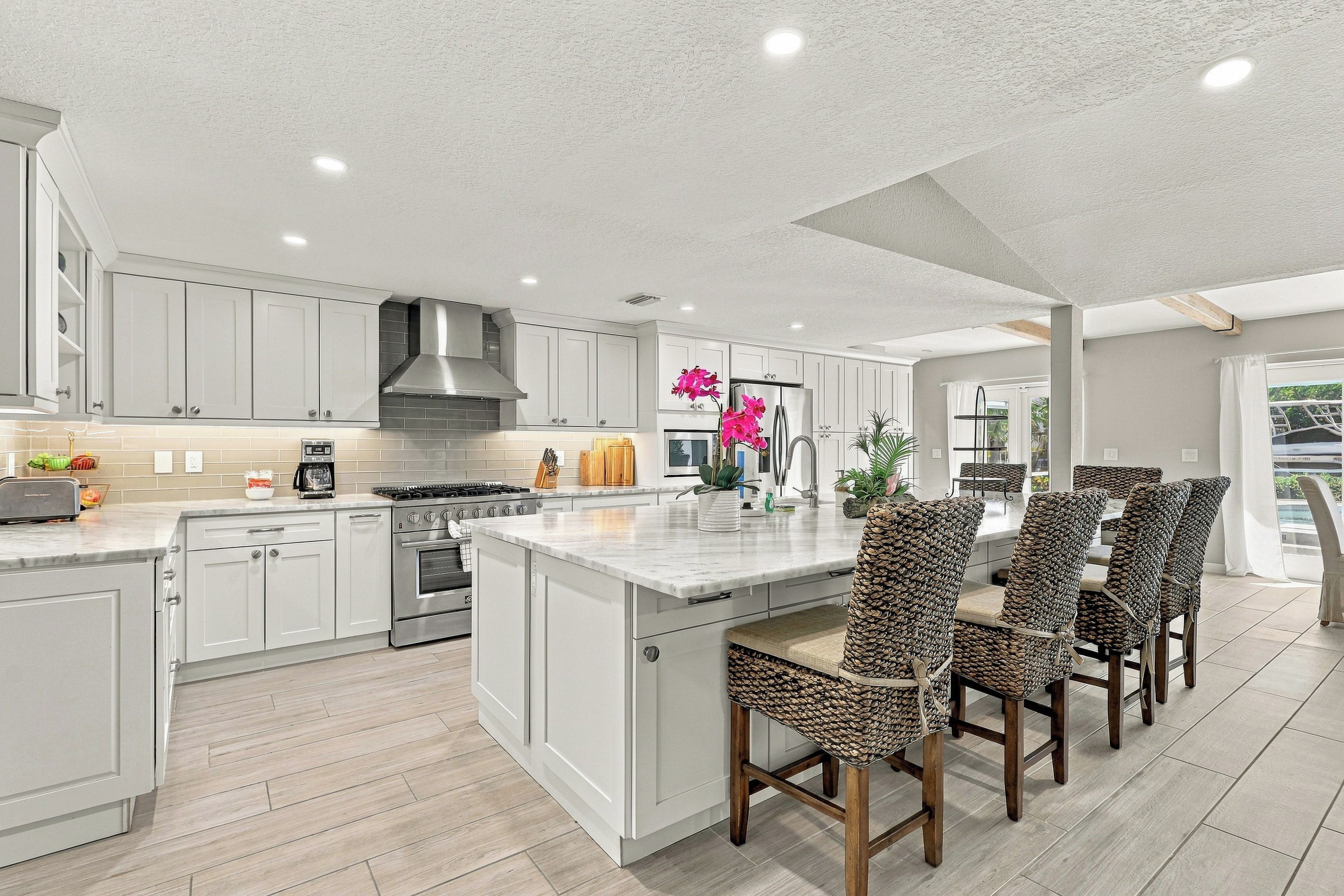 A spacious kitchen with a central island, modern appliances, and a dining area with wicker chairs.