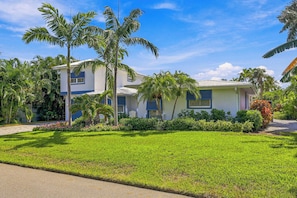 A two-story house with a well-maintained lawn and palm trees. - The Windquest Inn 3B / 3.5B + Den Private Canal Home by RVA (Longboat Key)