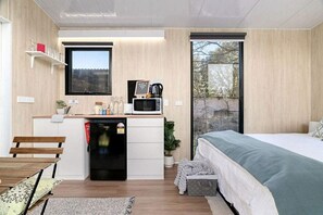 Une chambre compacte comprenant un lit, une petite kitchenette et une fenêtre.