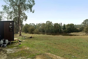 A fenced outdoor area with a small building, a pond, and trees in the background.