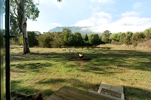 An outdoor area with a grassy field, a wooden deck, and a view of a mountain range.