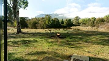 Área externa com gramado, deck de madeira e vista para uma cordilheira.