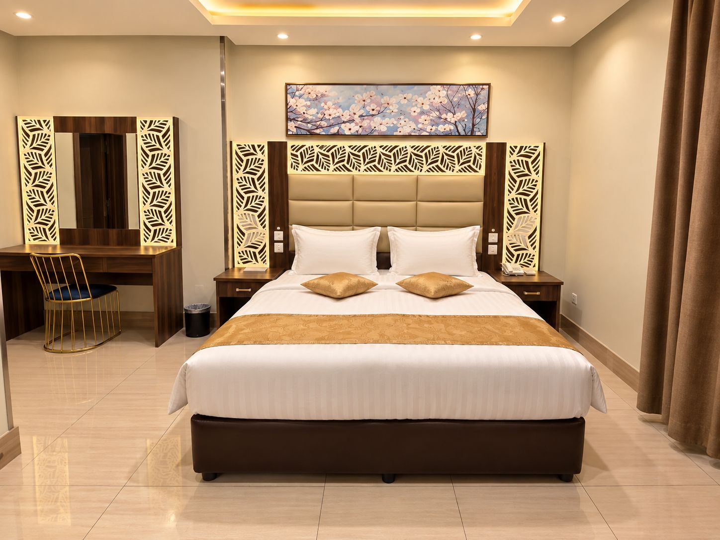 A hotel room with a large bed, a desk, and a chair. There is a painting on the wall and a decorative panel above the bed.