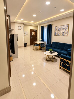 A modern living room with a blue sofa, a round coffee table, and a dining area with a white table and chairs. - Manazelna serviced apartments- economic (Jeddah)