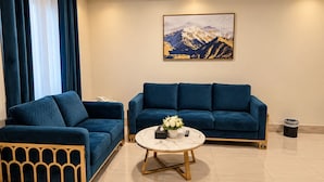 Uma sala de estar moderna com um sofá azul, uma mesa de centro e uma pintura de montanhas na parede.