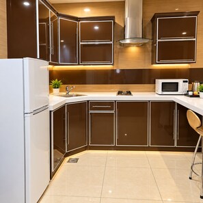 A modern kitchen with a white refrigerator, stainless steel sink, and a microwave. - Manazelna serviced apartments- economic (Jeddah)