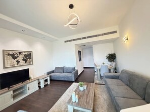 Ein modernes Wohnzimmer mit Fernseher, grauen Sofas, einem Couchtisch und einer Weltkarte als Wandkunst.
