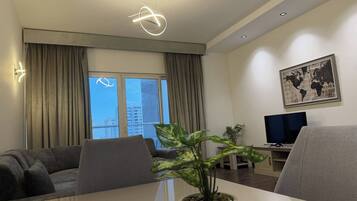 A modern living room with a sofa, a dining table with a plant, a television, and a world map on the wall.