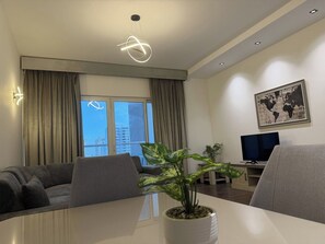 Una sala moderna con un sofá, una mesa de comedor con una planta, un televisor y un mapa mundial en la pared.