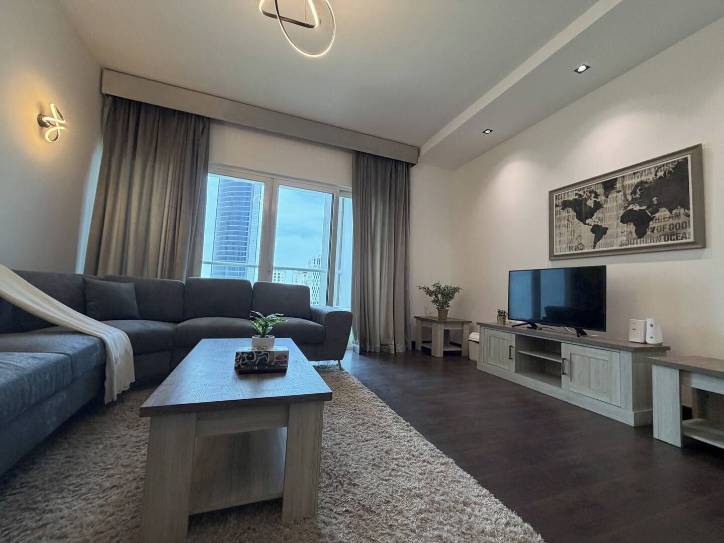 A modern living room with a sofa, a coffee table, a television, and a world map on the wall.