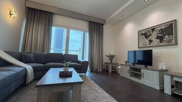 A modern living room with a sofa, a coffee table, a television, and a world map on the wall.