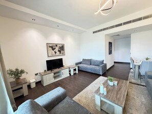 Una sala de estar moderna con un televisor de pantalla plana, sofás grises, una mesa de centro y una obra de arte con un mapa del mundo en la pared.