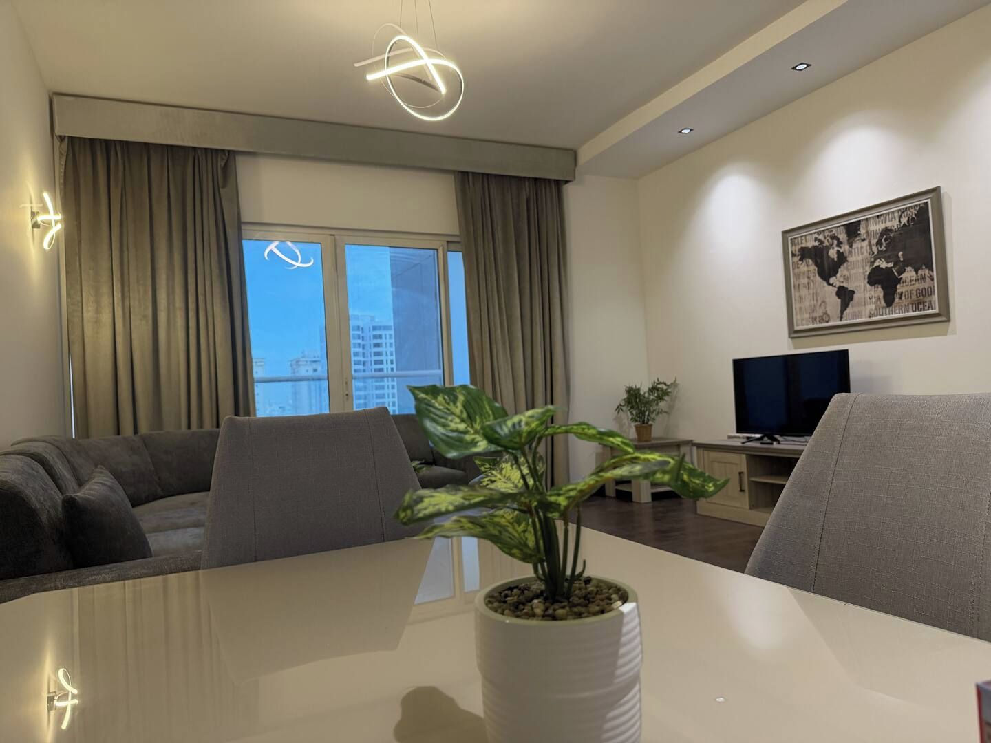 A modern living room with a sofa, a dining table, and a potted plant.