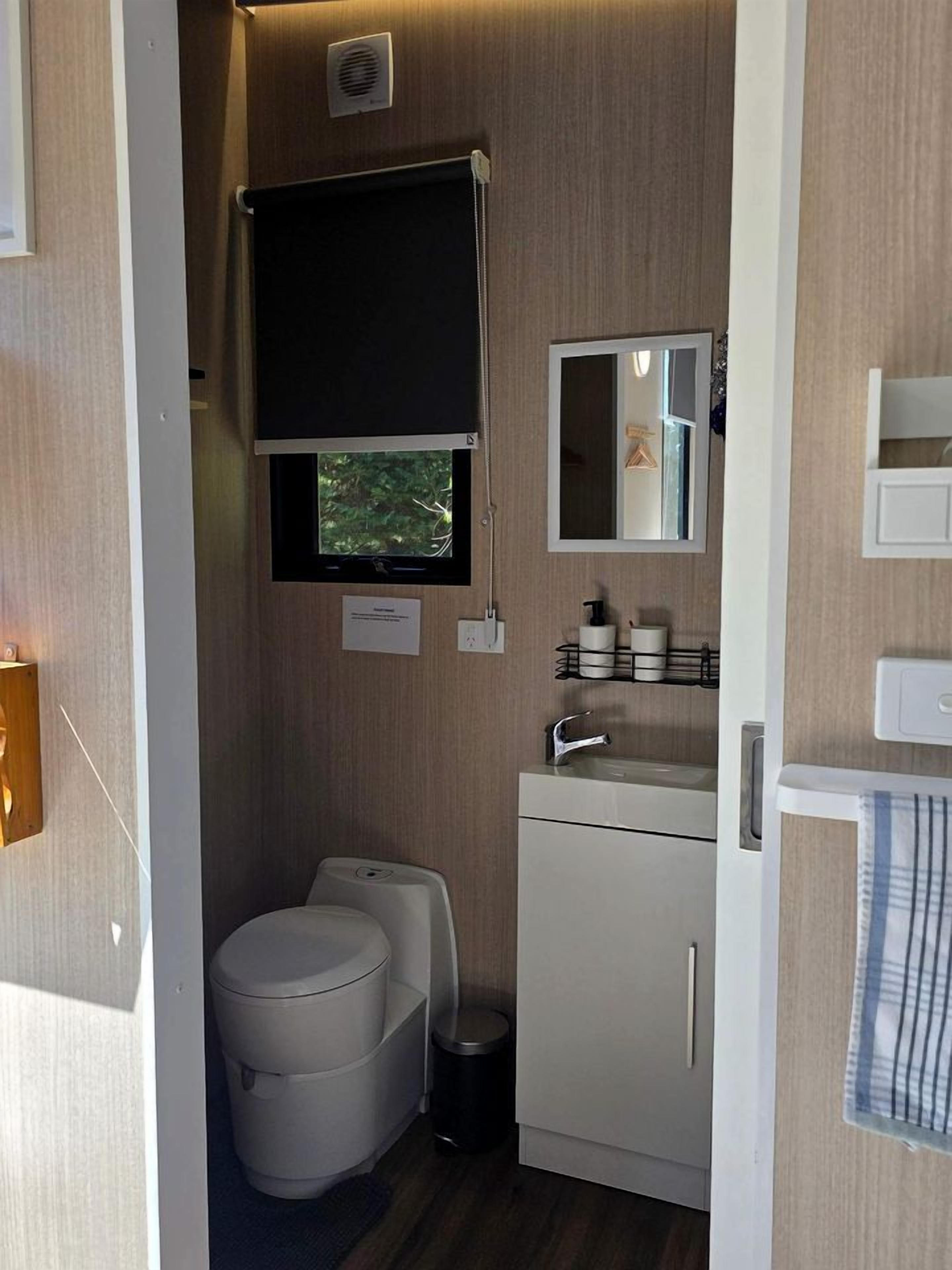 A compact bathroom with a toilet, sink, and mirror.