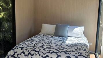 A modern bedroom with a bed, a window, and an air conditioning unit.