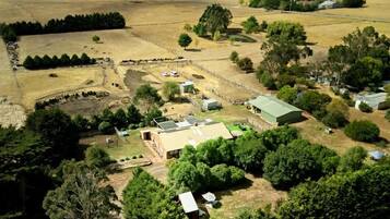 An aerial view of a rural property with a farmhouse, open fields, and scattered trees.