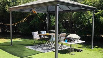 Un espacio al aire libre cubierto con una mesa, sillas, una parrilla y un generador eléctrico.