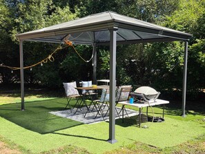 A covered outdoor area with a table and chairs, a grill, and a power generator.