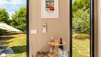 Una habitación moderna con una mesa de madera, un cuadro enmarcado y vistas a un jardín a través de amplios ventanales.