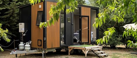 A compact, modern RV with a sleeping area, a small kitchen, and a portable toilet.