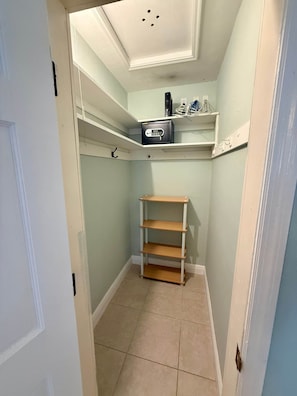 A narrow hallway with a white door on the left, a white ceiling with recessed lighting, and a small shelf unit with a safe on the wall. - Pompano Vibes Beach Apartments - Unit 2 "Coral Reef" (Pompano Beach)