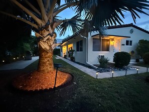 Ein Wohnhaus mit gepflegtem Rasen, einer Palme und einem Weg zum Eingang.